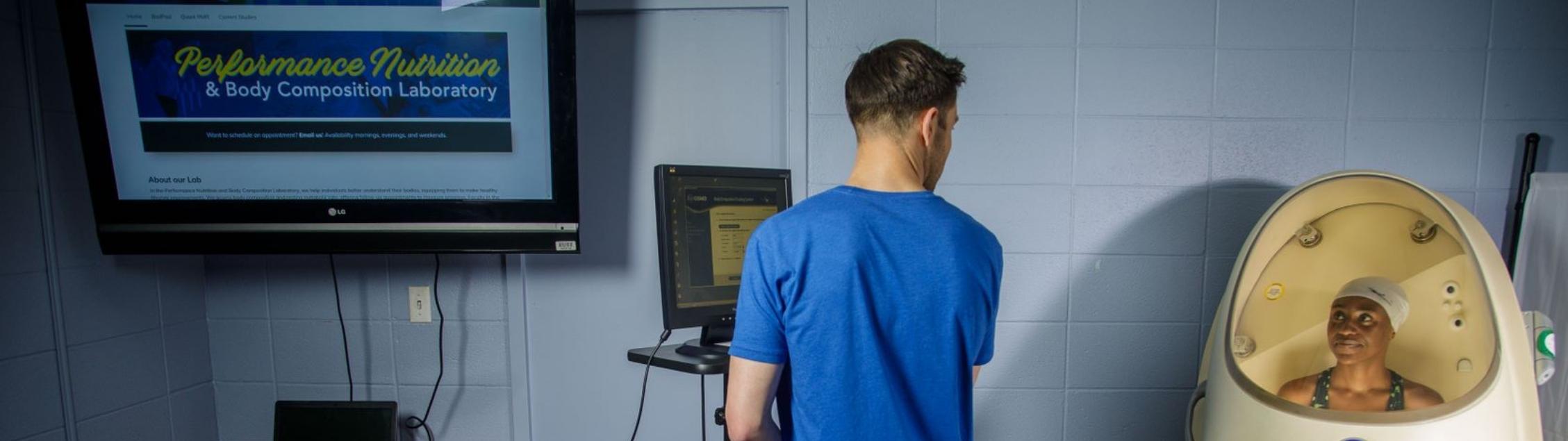 Student worker helps woman in BodPod